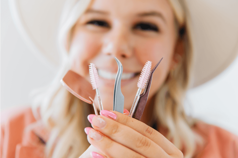 "Lexi stands smiling in front of several lash brushes and other lash artist equipment. Lexi is a lash artist located in American Fork, UT with openings for lash extension appointments.