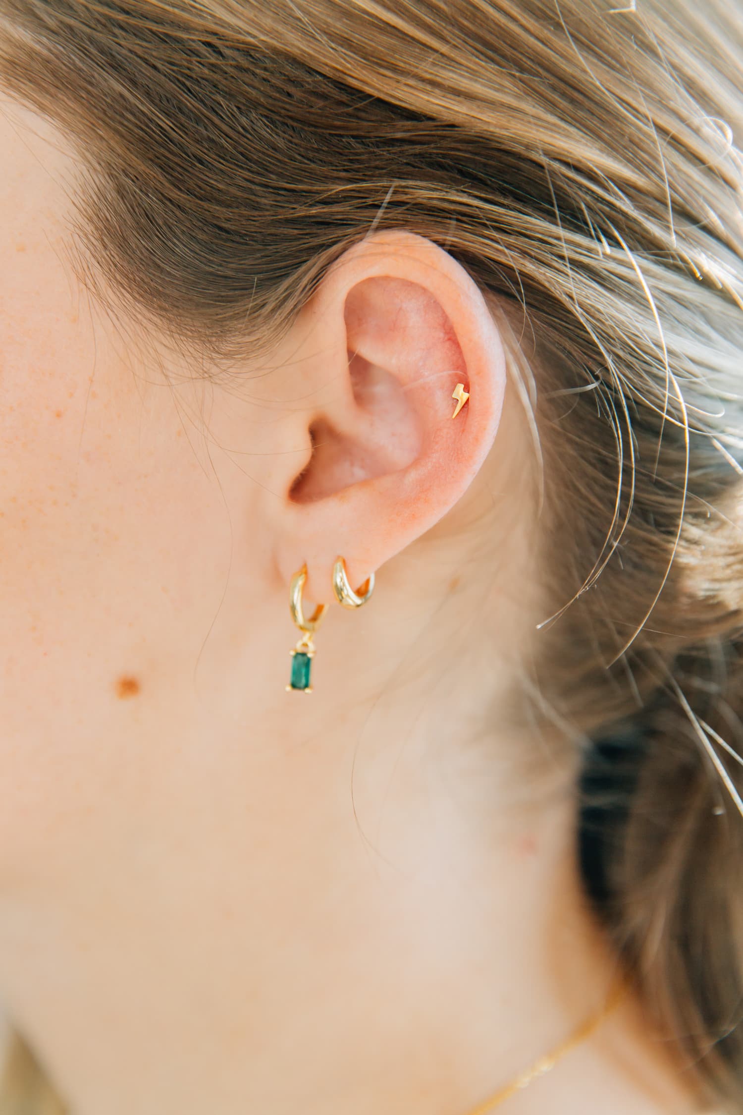 Lexi stands showing off her ear piercings. Get dainty ear piercings and jewelry at Aesthetics By Lex, located near American Fork, UT.